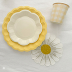 Detalle de platos amarillos troquelados y servilleta con forma de margarita de la colección El Jardín de las Margaritas; menaje premium para fiestas infantiles