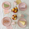 Set completo de decoración para fiesta de hadas y princesas con platos de cuadros vichy pastel, vasos, servilletas, gorritos de fiesta y confeti de estrellas sobre un mantel blanco.